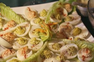stuffed eggs with wasabi and avocado White plate with stuffed eggs with wasabi and avocado and lettuce leaves as a garnish