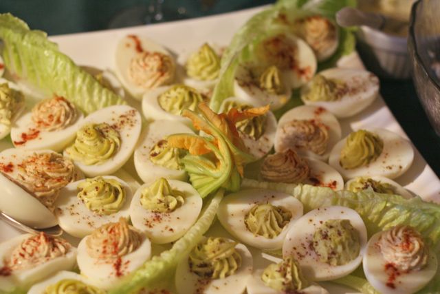 White plate with stuffed eggs with wasabi and avocado and lettuce leaves as a garnish